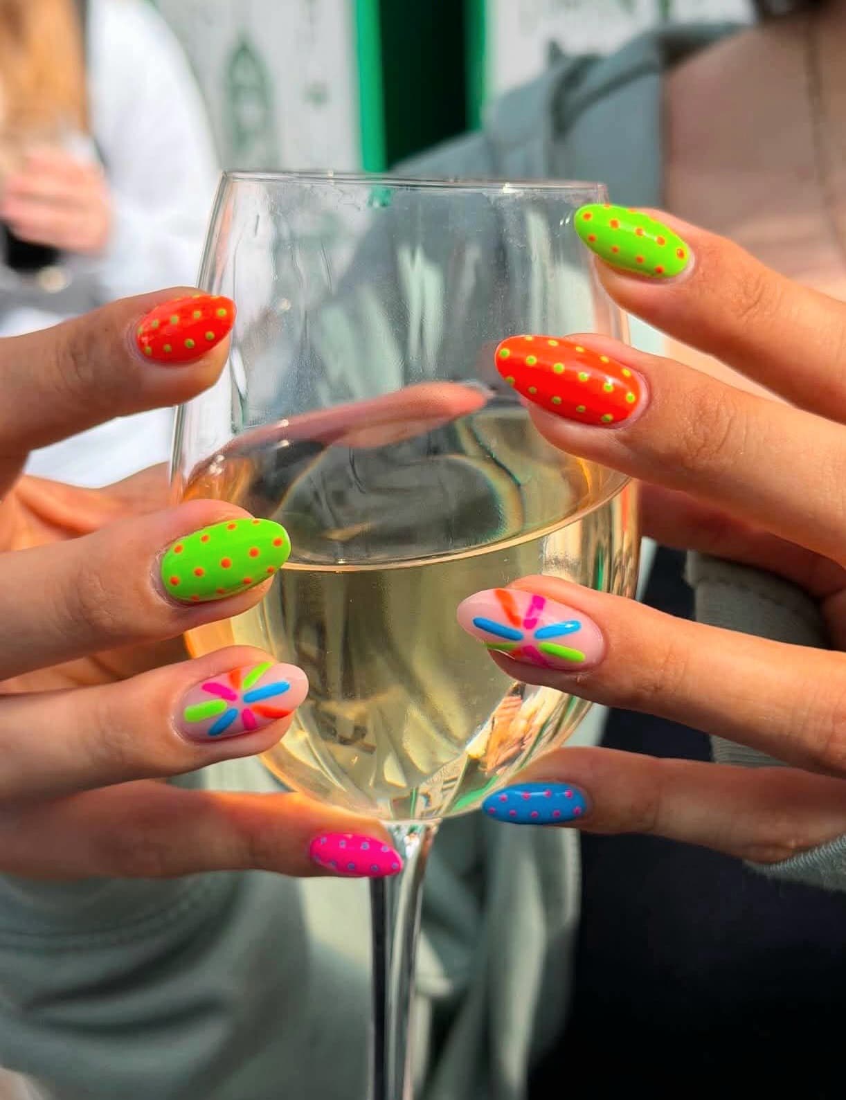 Neon dotted manicure beside a wine glass by Blackrock Nails & Spa